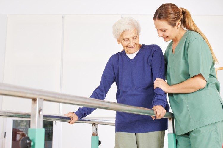 physiotherapist helping old senior woman